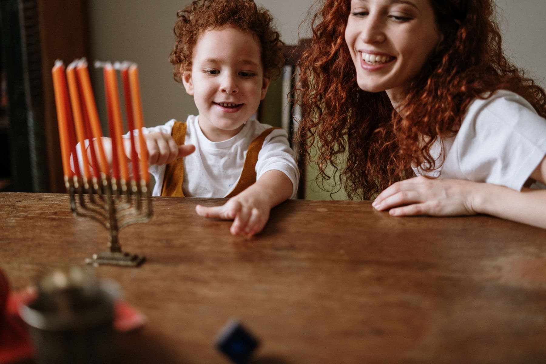 Mother and young son smiling beside a Chanukah menorah