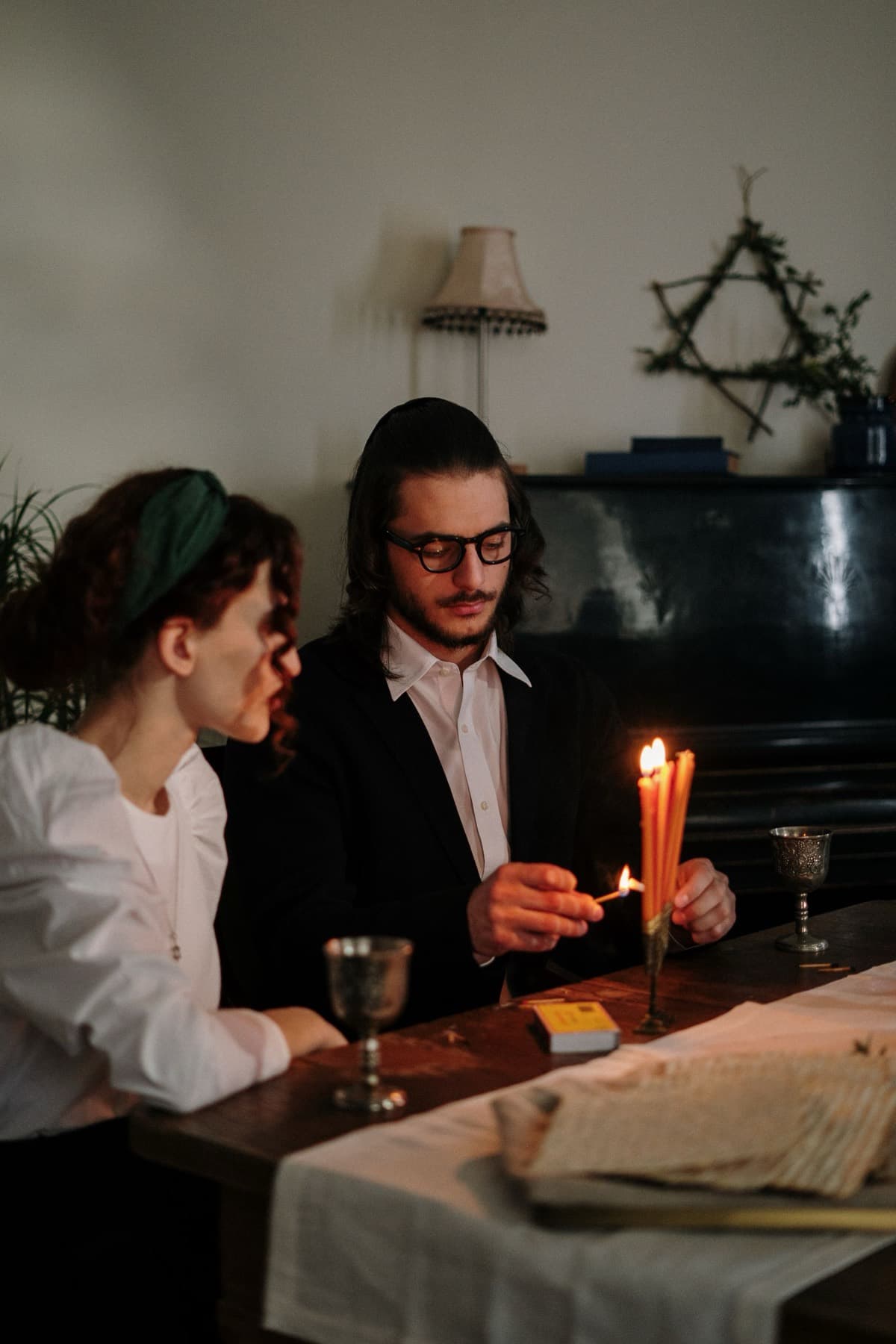 Couple lighting two candles at a set table