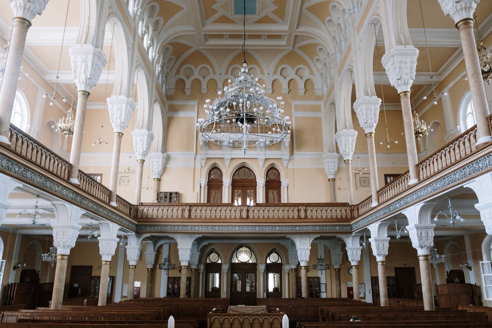 Bright synagogue sanctuary with arched columns and a chandelier